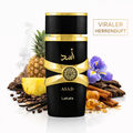 Schwarzer und goldener Parfumflakon „ASAD“ von Lattafa mit dekorativem Goldemblem, inszeniert vor Ananas, Vanilleschoten, Kaffeebohnen, Zimt, Harz und lila Blüte; daneben der Schriftzug „Viraler Herrenduft“.