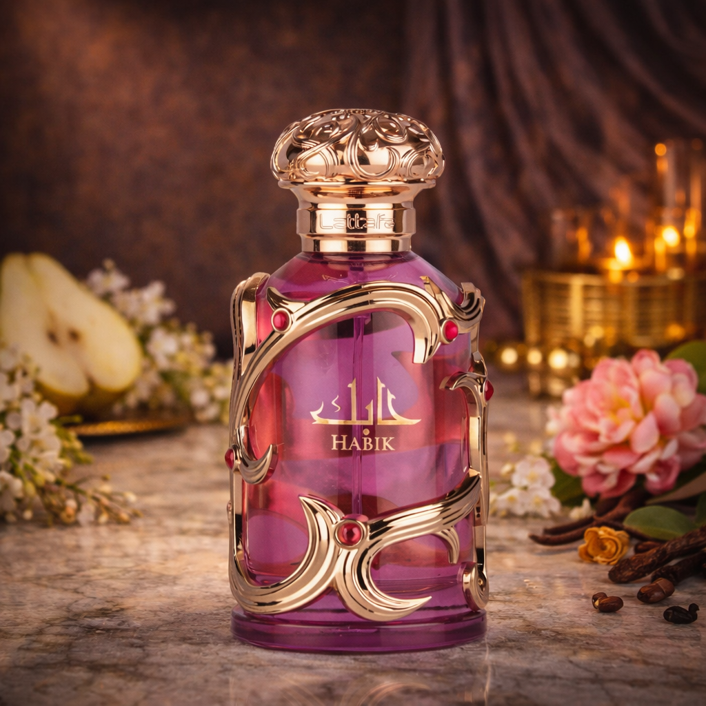 Lattafa „Habik“ Eau de Parfum im violetten Glasflakon mit goldenen Ornamentdetails und roséfarbenem Verschluss, inszeniert auf Marmoroberfläche mit Birne, weißen Blüten, rosa Blume, Gewürzen und warmem Kerzenlicht im Hintergrund.