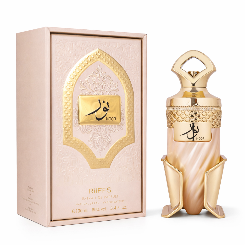 Luxuriöses Extrait de Parfum „Noor“ von Riiffs (100 ml) mit edlem, goldverziertem Flakon und passender rosé-goldener Verpackung. Der kunstvoll gestaltete Flakon mit arabischer Schrift und ornamentalen Details steht neben der dekorativen Box auf hellem Hintergrund und unterstreicht den eleganten, orientalischen Charakter des Duftes.