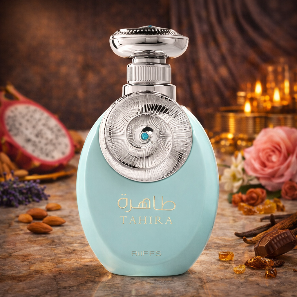 Türkisfarbener, ovaler Parfumflakon „Tahira“ von RIIFFS mit silbernem, kunstvoll verziertem Verschluss und rundem Ornament mit türkisfarbenem Stein in der Mitte. Der Flakon steht auf einer warm beleuchteten Oberfläche, umgeben von Mandeln, Vanilleschoten, Pralinenstücken, Rosenblüten und einer halbierten Drachenfrucht im Hintergrund.